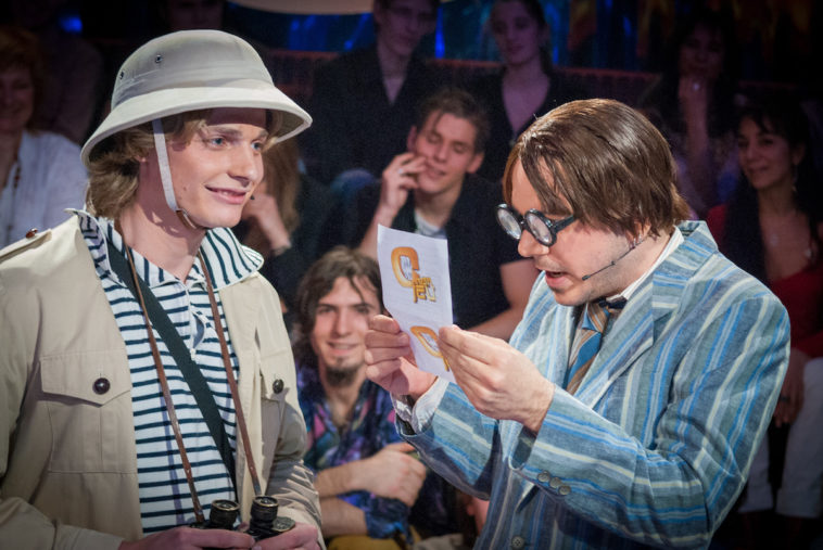 Sarkis Ohanessian, alias "Sarcouince", présente la finale de "C mon jeu", comedy game de la Radio Télévision Suisse. Il est vêtu d'une veste rayée moche, porte de grosses lunettes épaisses et est mal coiffé. Il a à côté de lui un candidat habillé en explorateur avec un casque colonial.